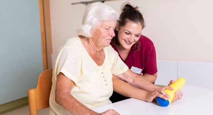 Therapeutin unterstützt ältere Patientin in der Ergotherapie
