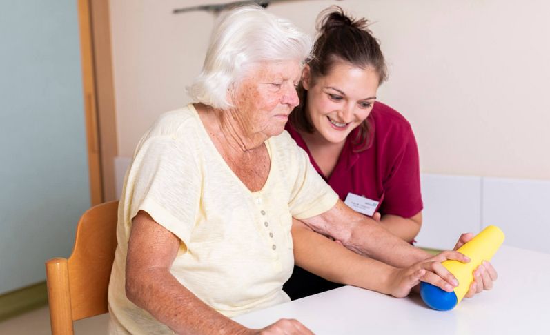 Therapeutin unterstützt ältere Patientin in der Ergotherapie