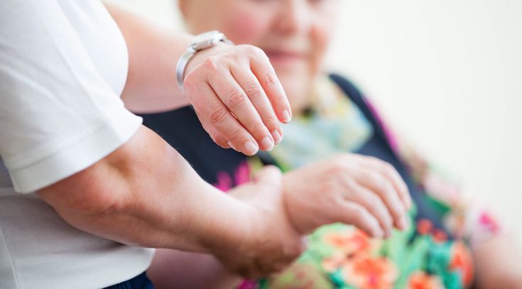 Pflegekraft misst Puls einer Patientin