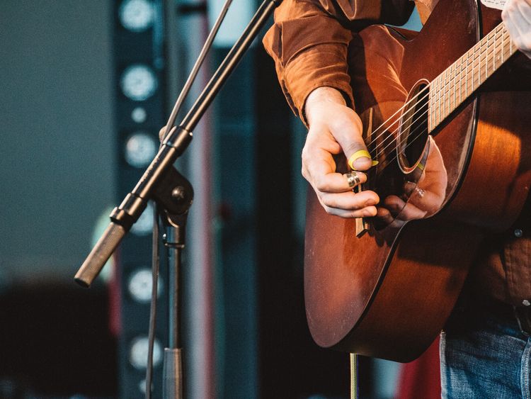 Musiker spielt Giarre auf der Bühne vor einem Mikrophone