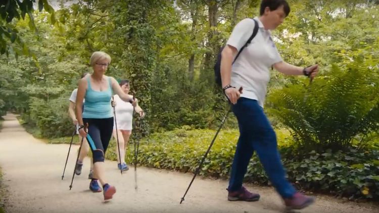 Patienten wandern mit Nordic Walking Stöcken durch den Wald