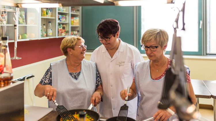 Patienten und Therapeutin kochen in der Lehrküche