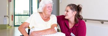 Pflegerin spricht mit Patientin im Rollstuhl