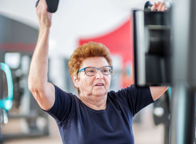Trainingstherapie Ältere Patientin stärkt ihre Muskeln an Geräten in der medizinischen Trainingstherapie